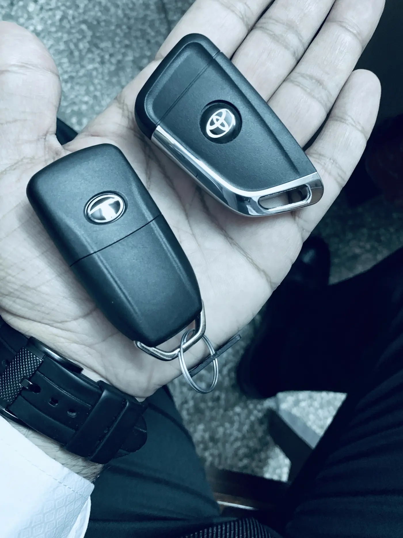 Two black vehicle remote keys held in one hand